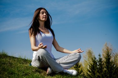 güzel bir genç kadın çim yama üzerinde meditasyon