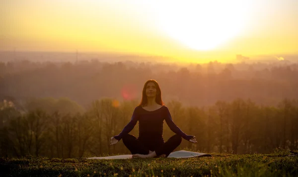 güzel bir genç kadın çim yama üzerinde meditasyon