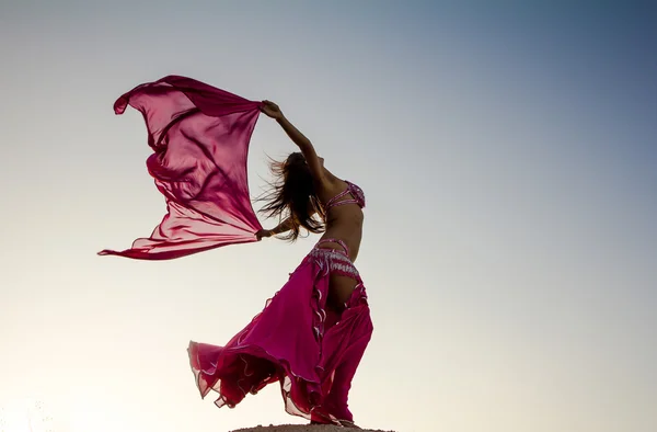 Chica bonita sosteniendo tela rosa en el viento con el fondo del cielo Fotos de stock libres de derechos