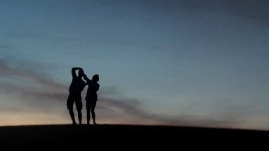 rahat genç pasionate çift balayında turuncu arka plan ile bir çölde günbatımı güzellik zevk