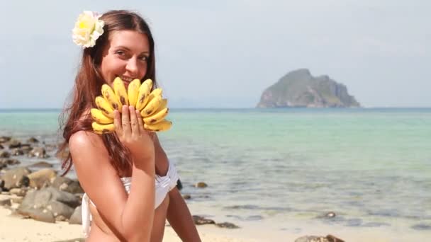 Jeune femme se détendre sur la plage et manger des fruits — Video