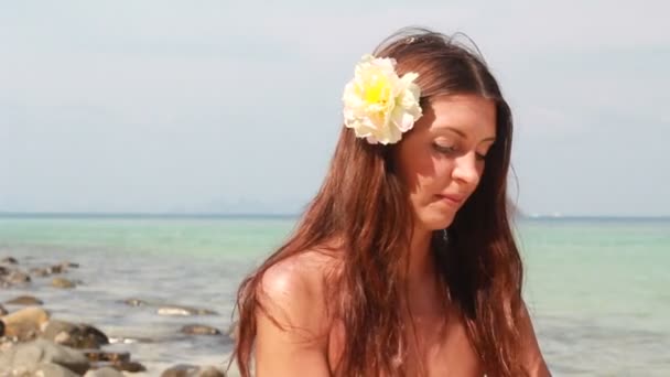 Junge Frau entspannt sich am Strand und isst Früchte — Stockvideo