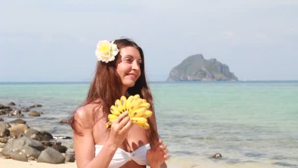 Jonge vrouw ontspannen op het strand en het eten van vruchten — Stockvideo