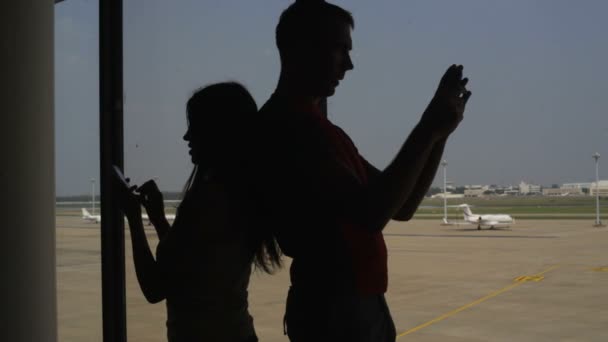 Silhouette of pair of lovers near the window in airport — Stock Video