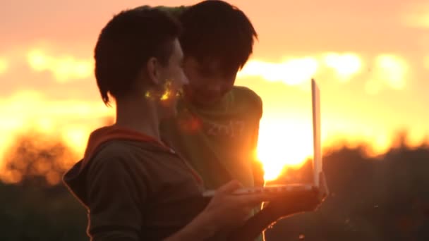 Teenagers with laptop resting on meadow. — Stock Video