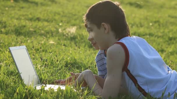 Adolescentes con portátil descansando en el prado . — Vídeo de stock