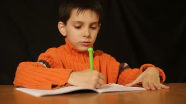 Çocuk bir not defterinde yazıyor