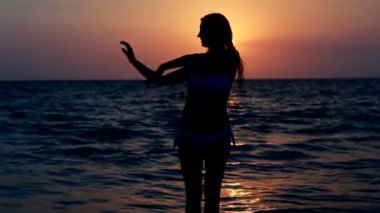 mutlu bir kadın deniz arka plan ile gün batımında sahilde dans