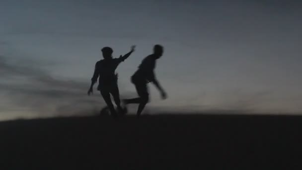 Ontspannen jong pasionate koppel genieten van de zonsondergang schoonheid op hun huwelijksreis, op een woestijn met oranje achtergrond — Stockvideo