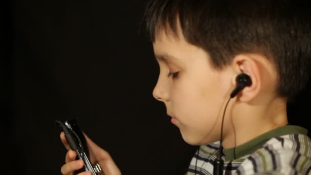 Хлопчик слухає музику по телефону . — стокове відео