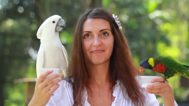 Leende flicka med färgglada papegoja i djungeln — Stockvideo