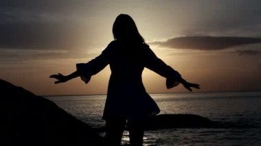 mutlu bir kadın deniz arka plan ile gün batımında sahilde dans