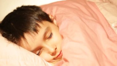 Çocuk uyuyor, yatağında rüya görüyor.