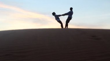 rahat genç pasionate çift balayında turuncu arka plan ile bir çölde günbatımı güzellik zevk