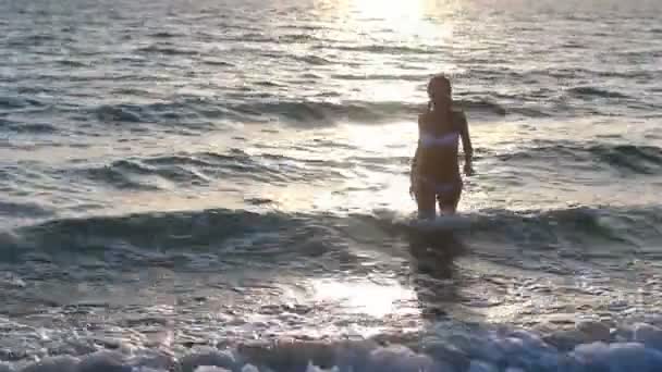 Silhouette d'une fille dans l'eau au coucher du soleil .
