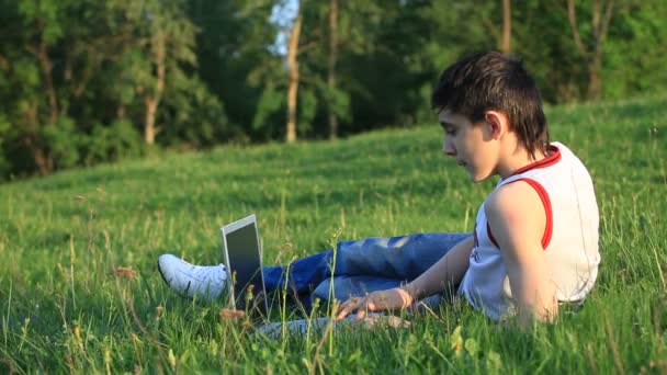 Teenager with laptop resting on meadow — Stock Video