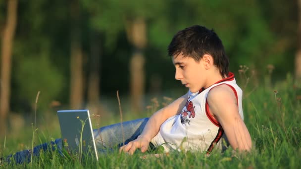 少年与笔记本电脑在草地上休息 — 图库视频影像