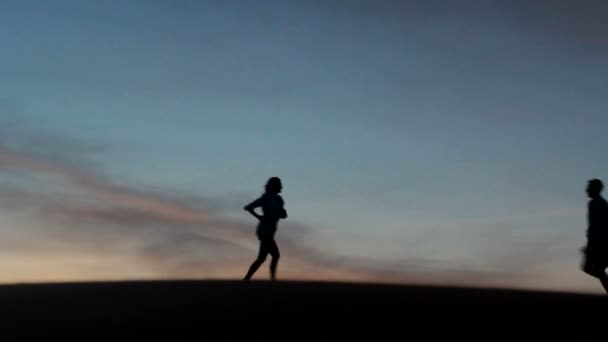 Relax giovane coppia pasionate godendo la bellezza del tramonto in luna di miele, su un deserto con sfondo arancione — Video Stock