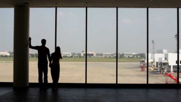 Silueta de pareja de amantes cerca de la ventana en el aeropuerto — Vídeo de stock