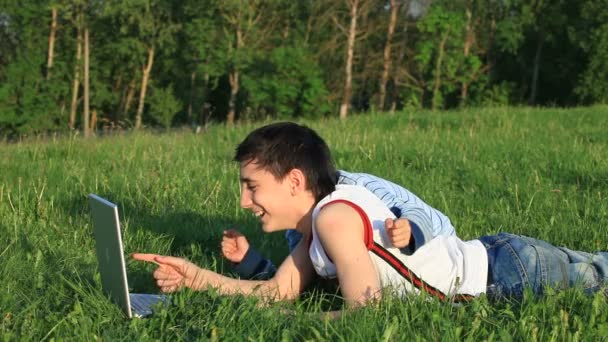 Teenagers with laptop resting on meadow. — Stock Video