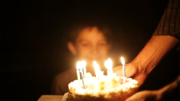 Chico sopla velas en pastel de cumpleaños . — Vídeos de Stock