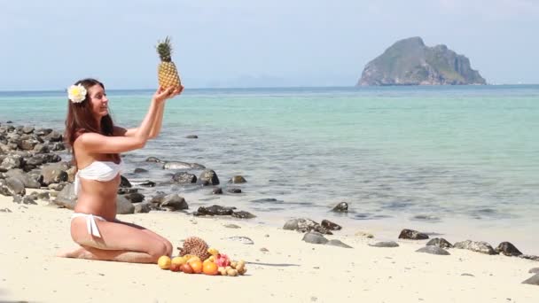 Mujer joven relajándose en la playa y comiendo frutas — Vídeo de stock