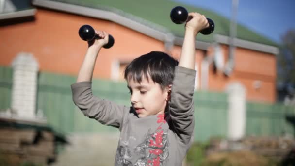 Boy lifting dumbbells — Stock Video