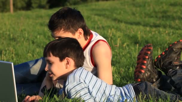 Teenagers with laptop resting on meadow. — Stock Video