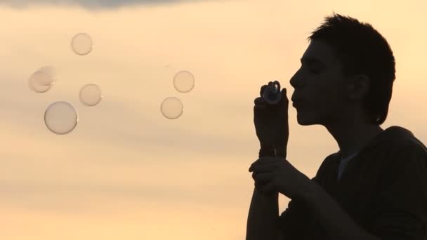 Хлопчик дме бульбашки в полі — стокове відео