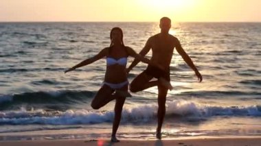 bir çekici genç bir kadın ve bir iskele ile okyanus üzerinde yoga yapan erkek