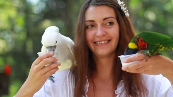 Улыбающаяся девушка с разноцветным попугаем в джунглях — стоковое видео