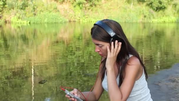 Chica con auriculares por el lago — Vídeos de Stock