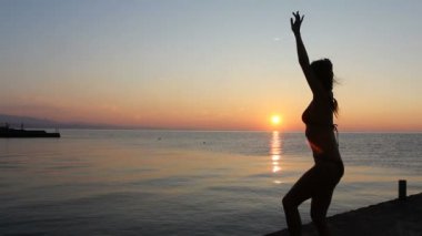 mutlu bir kadın deniz arka plan ile gün batımında sahilde dans