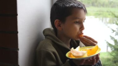 Çocuk bir portakal yiyor