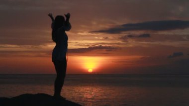 Deniz arka plan ile gün batımında sahilde dans kadın