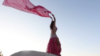 güzel kız pembe bir bez Rüzgar gökyüzü arka plan ile holding