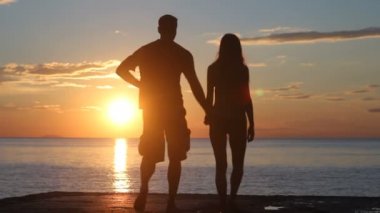 Sahilde iki siluet. günbatımı ışığı.