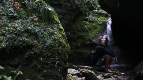 Der Mann trinkt aus einem Wasserfall — Stockvideo