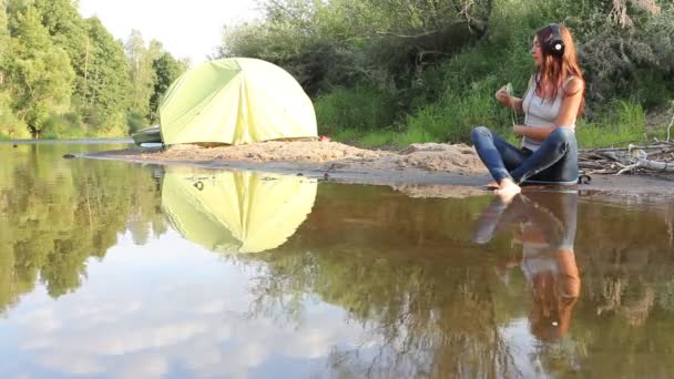 Girl with headphones by lake — Stock Video