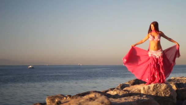 Счастливая женщина танцует на пляже на закате на фоне моря — стоковое видео