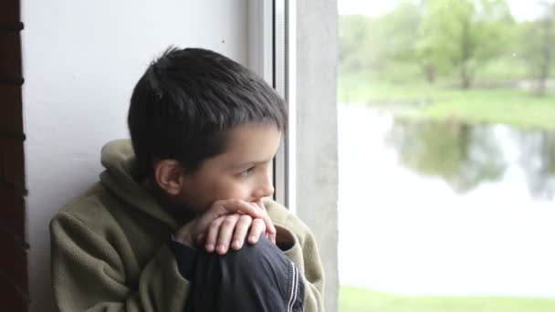 Jongen op zoek door het raam en dromen — Stockvideo