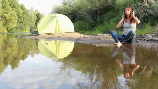 Девушка в наушниках у озера — стоковое видео
