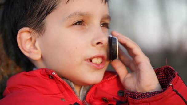 Boy talking on mobile phone outdoors — Stock Video