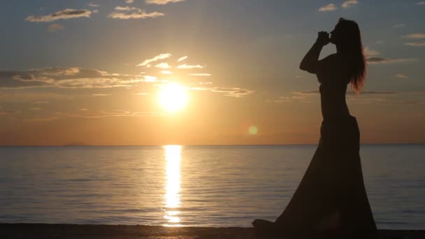 Glückliche Frau tanzt am Strand bei Sonnenuntergang mit Meereshintergrund — Stockvideo