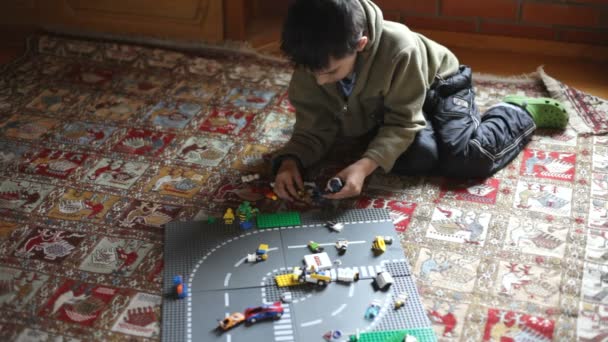 Мальчик играет с разноцветными игрушечными машинами — стоковое видео