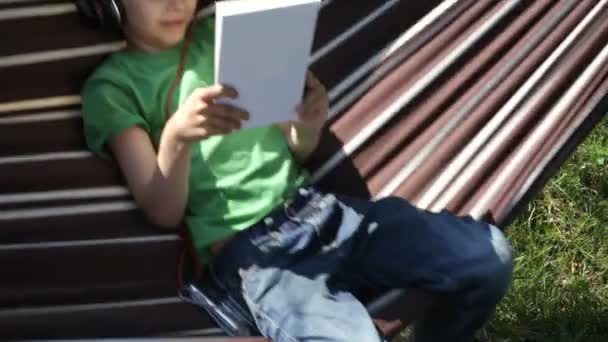 Pojke läsning i hängmattan — Stockvideo