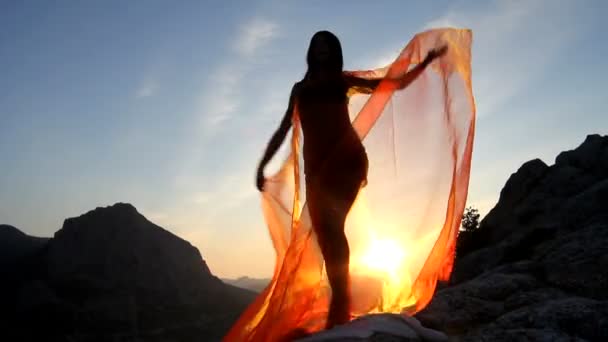 Mooi meisje houden van roze doek in wind met hemelachtergrond — Stockvideo