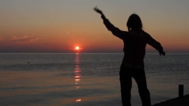 Mutlu bir kadın deniz arka plan ile gün batımında sahilde dans — Stok video