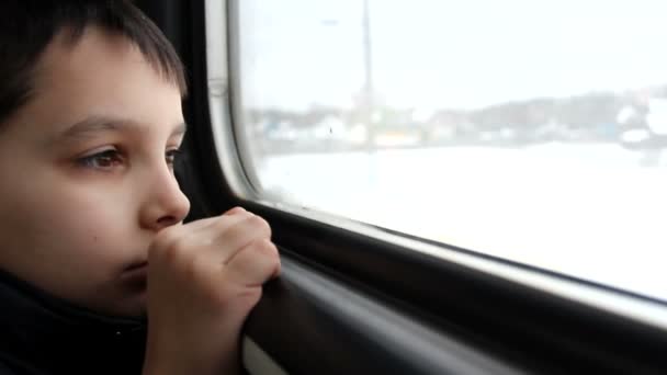 Rapaz olha pela janela do comboio — Vídeo de Stock