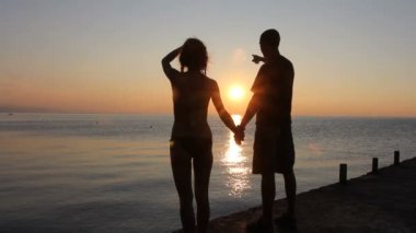 Sahilde iki siluet. günbatımı ışığı.